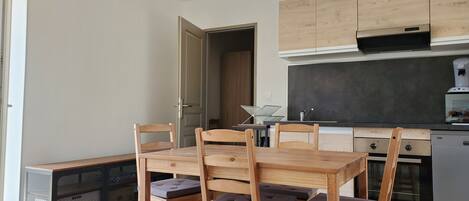 Eine kleine Küche mit Holzausstattung, einem eingebauten Ofen und einem Essbereich mit Tisch und Stühlen.