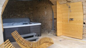 Ein Wellnessbereich mit Whirlpool, Holzboden und Dusche.