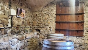 Ein rustikaler Keller mit Steinwänden, Holzbärigen und einem Weinschlauch.