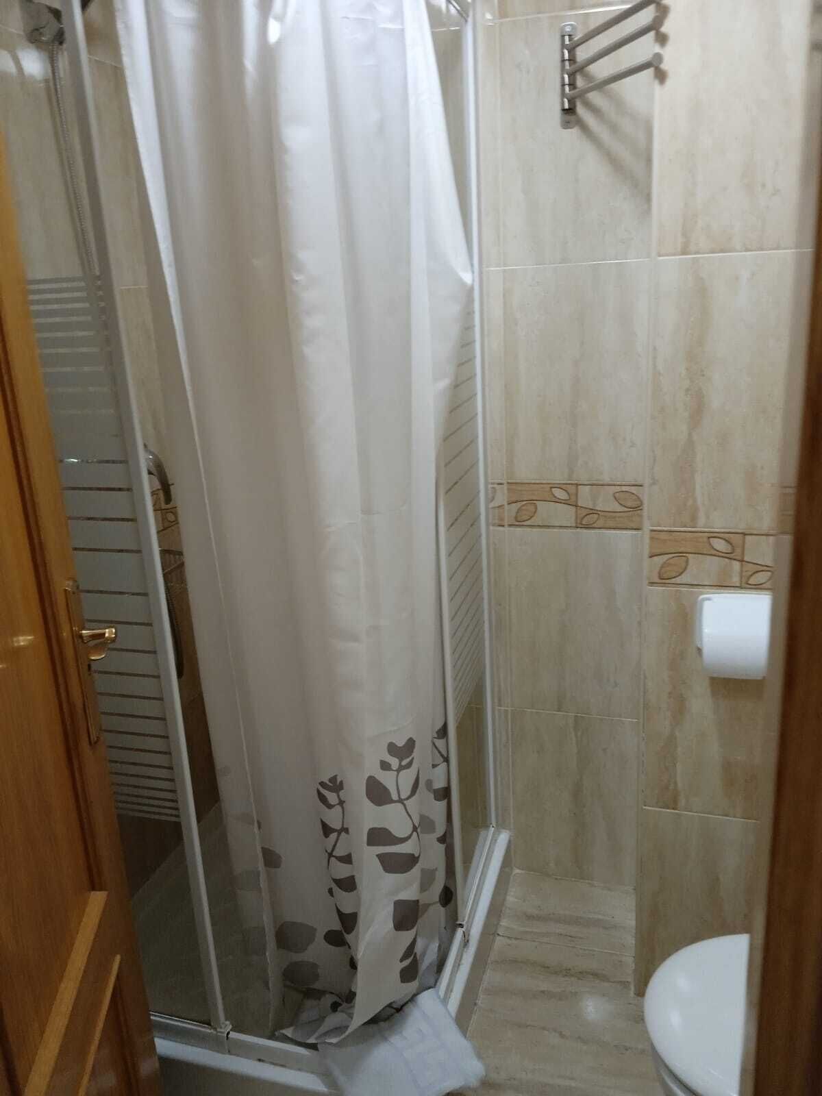 A bathroom with a glass shower enclosure, a toilet, and a towel rack.