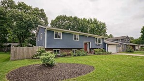 A two-story residential house with a front yard, a small garden, and a wooden fence. - Elegant Space–Premium Kitchen–Spacious & Ideal for Gathering w/ Friends & Family (Middleton)
