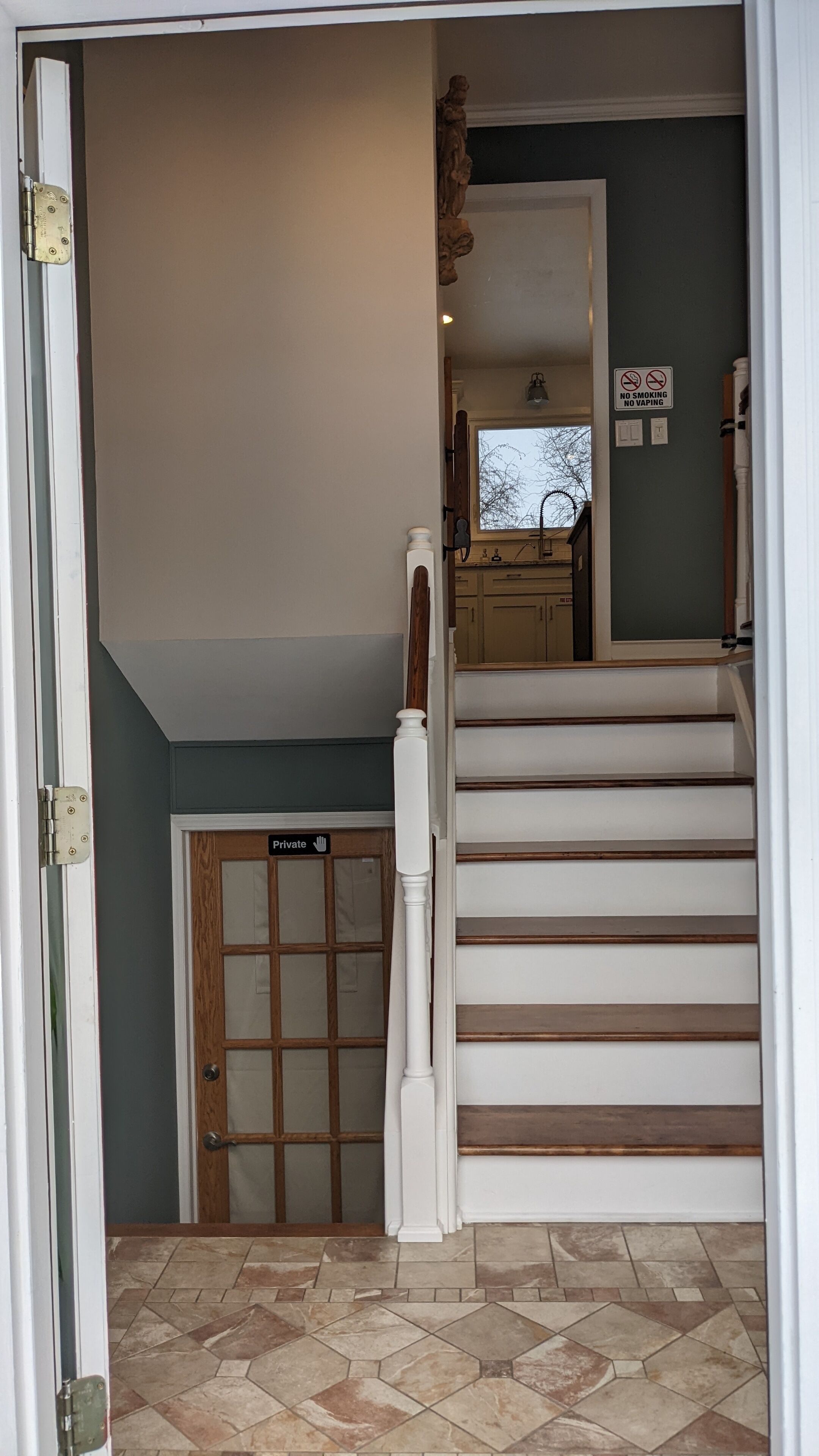 Un escalier avec une rampe, une porte avec une indication de « ne pas déranger » et une fenêtre donnant sur des arbres.