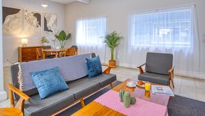 A modern living room with a sofa, armchairs, a dining table, and artwork on the walls. - Mai Calli Home Rentals (Mexico City)