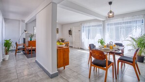 A spacious dining area with a wooden table and chairs, a potted plant, and a modern pendant light. - Mai Calli Home Rentals (Mexico City)