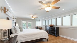 Ein geräumiges Schlafzimmer mit einem großen Bett, einem Deckenventilator und einer Kommode.
