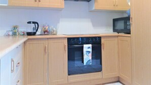 A compact kitchen with wooden cabinets, a microwave, a kettle, and a toaster. - Spacious holiday home in cozy complex. Walking distance from the nature reserve. (KZN)