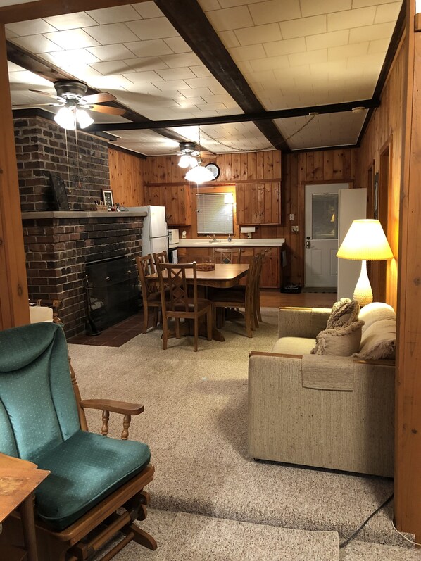 Una habitación acogedora con chimenea, muebles de madera, una mesa de comedor y una zona de cocina.