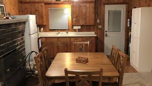 A wooden-paneled kitchen with a dining table and chairs, a refrigerator, and a ceiling fan. - Fence Lake Retreat w/ dock (Lac du Flambeau)