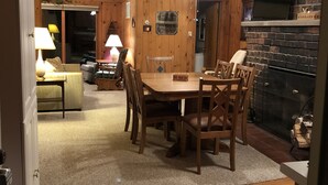 A cozy dining area with a wooden table and chairs, a ceiling fan, and a brick fireplace. - Fence Lake Retreat w/ dock (Lac du Flambeau)