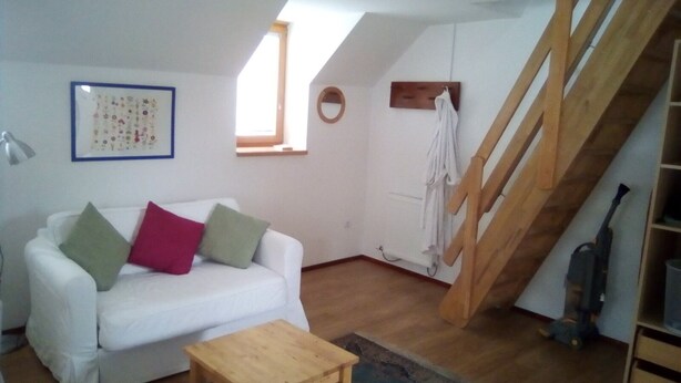 A white sofa with green and red cushions, a small wooden table, and a colorful rug. - No 2 Old Town Apts is in the centre of Bohinjska Bistrica, close to amenities. (Radovljica)