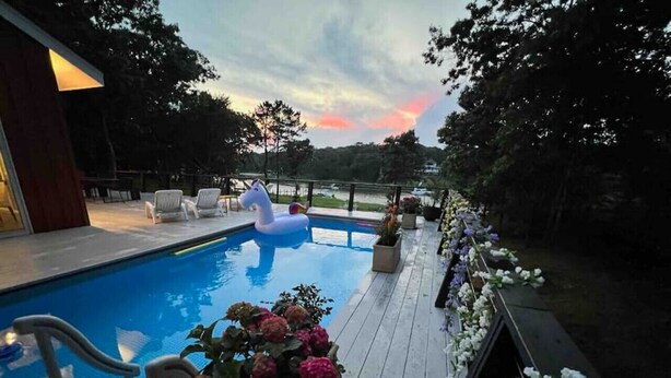 Uma área de piscina com bóia de unicórnio, espreguiçadeiras e um arranjo floral.