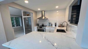 Uma cozinha moderna com uma grande ilha de mármore, eletrodomésticos de aço inoxidável e uma bancada elegante.