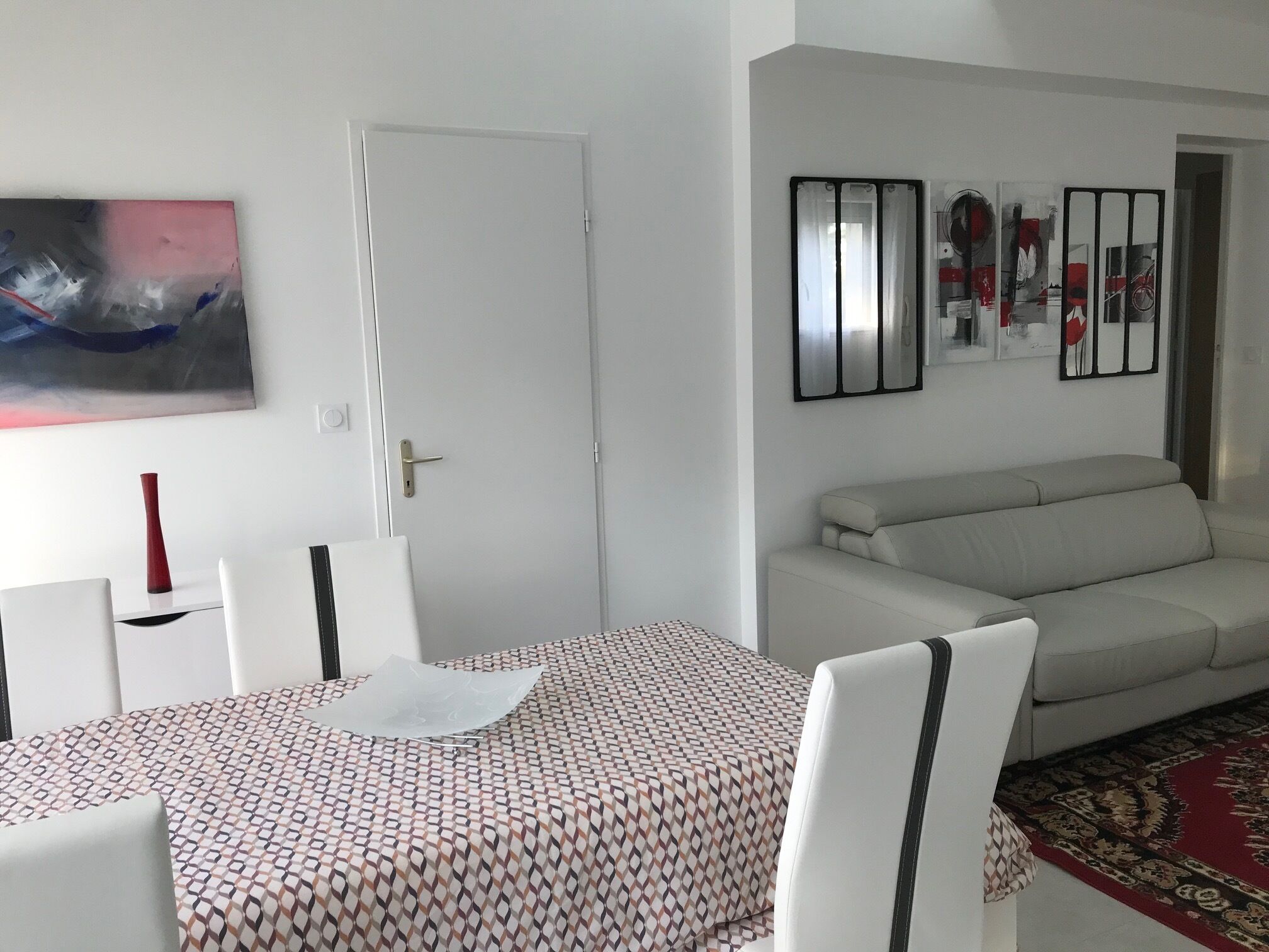 Ein modernes Wohnzimmer mit einer Couch, einem Esstisch mit Stühlen und einem Bild an der Wand.