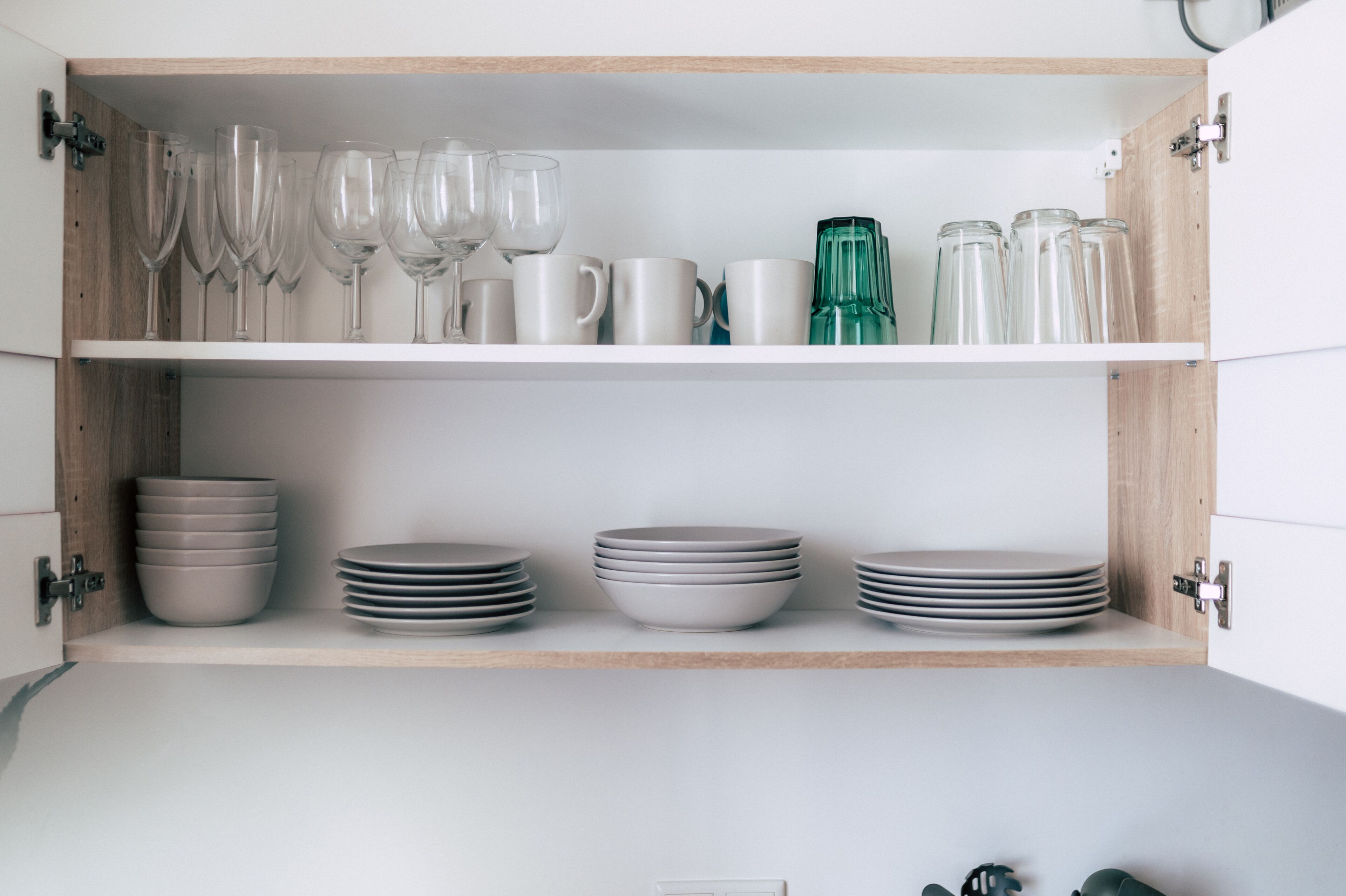 Un meuble de cuisine doté d’étagères où sont rangés divers objets en verre et assiettes.