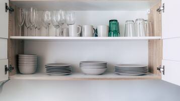 Un meuble de cuisine doté d’étagères où sont rangés divers objets en verre et assiettes.