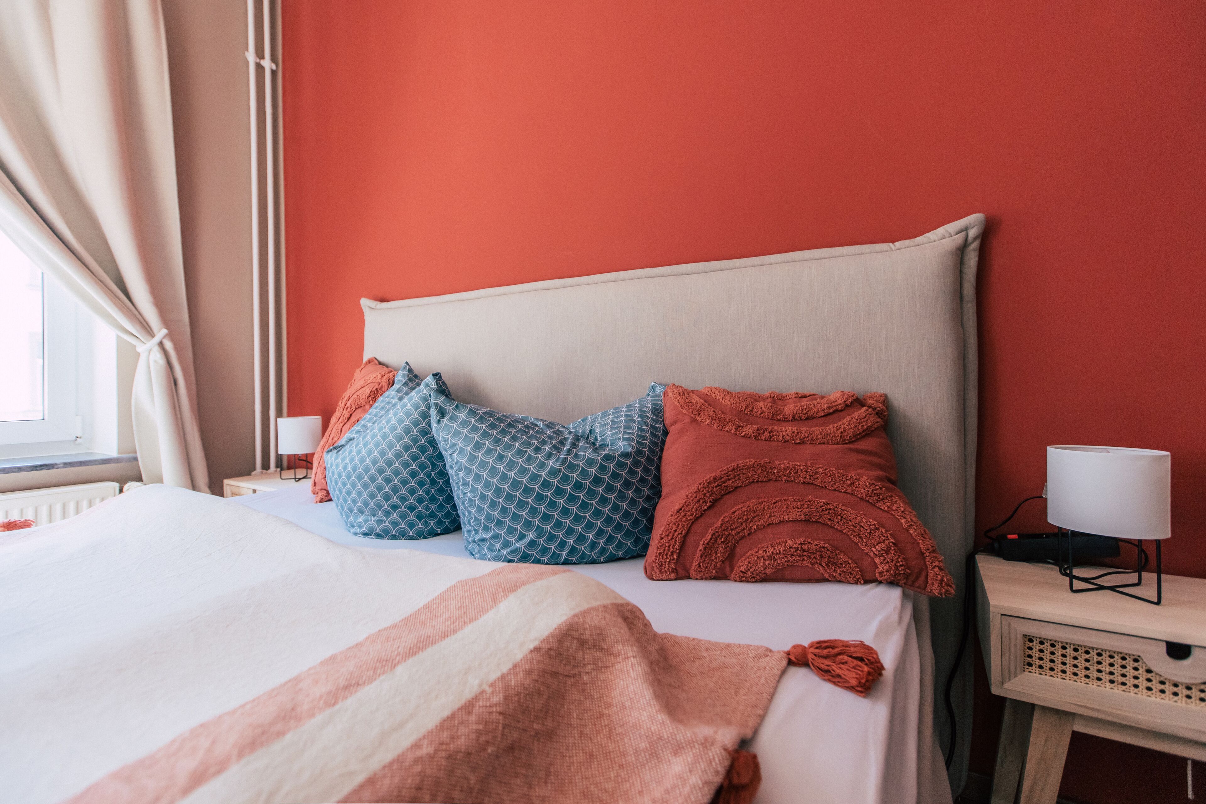 A neatly made bed with patterned pillows, a bedside lamp, and a nightstand with a lamp.