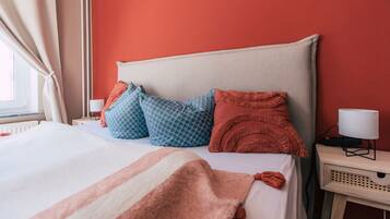 A neatly made bed with patterned pillows, a bedside lamp, and a nightstand with a lamp.