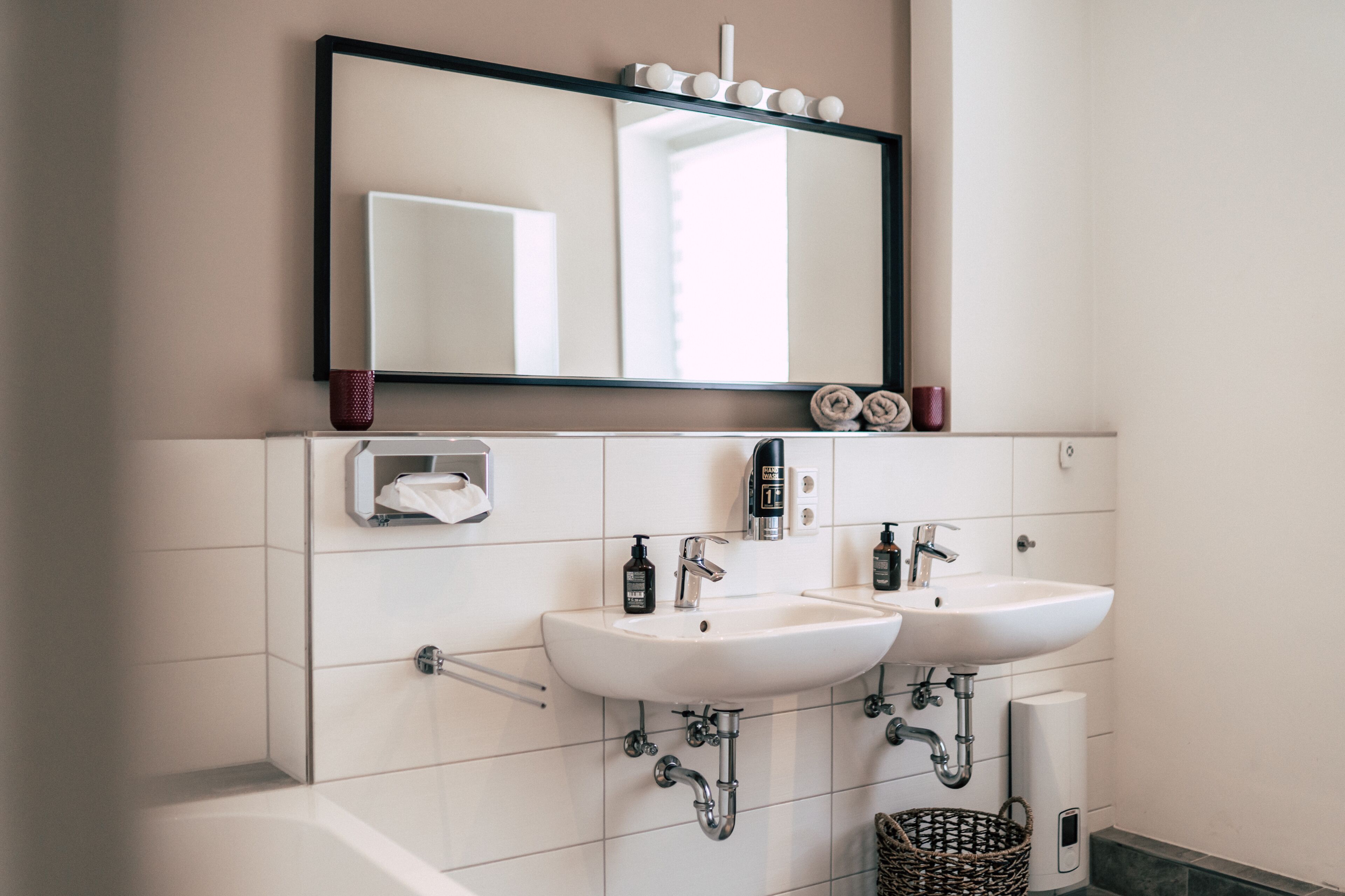 Une salle de bain avec deux lavabos, un miroir et un porte-serviettes.