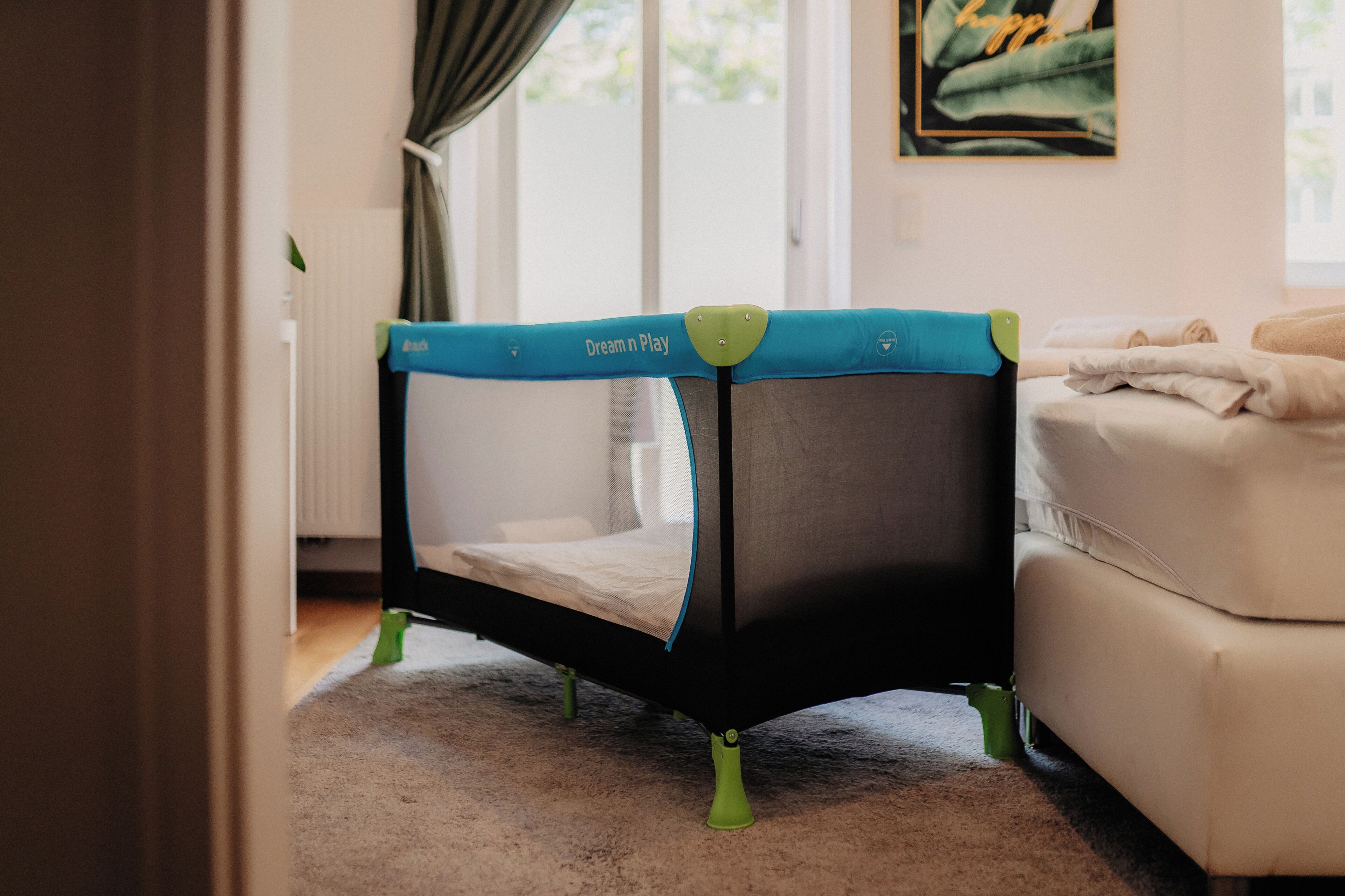A room with a crib, a sofa, and a window with curtains.