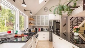 A modern kitchen with white cabinets, a stainless steel refrigerator, and a large window providing a view of trees. - Luxury Private Estate Mins to Winery /Brewery (Leesburg)