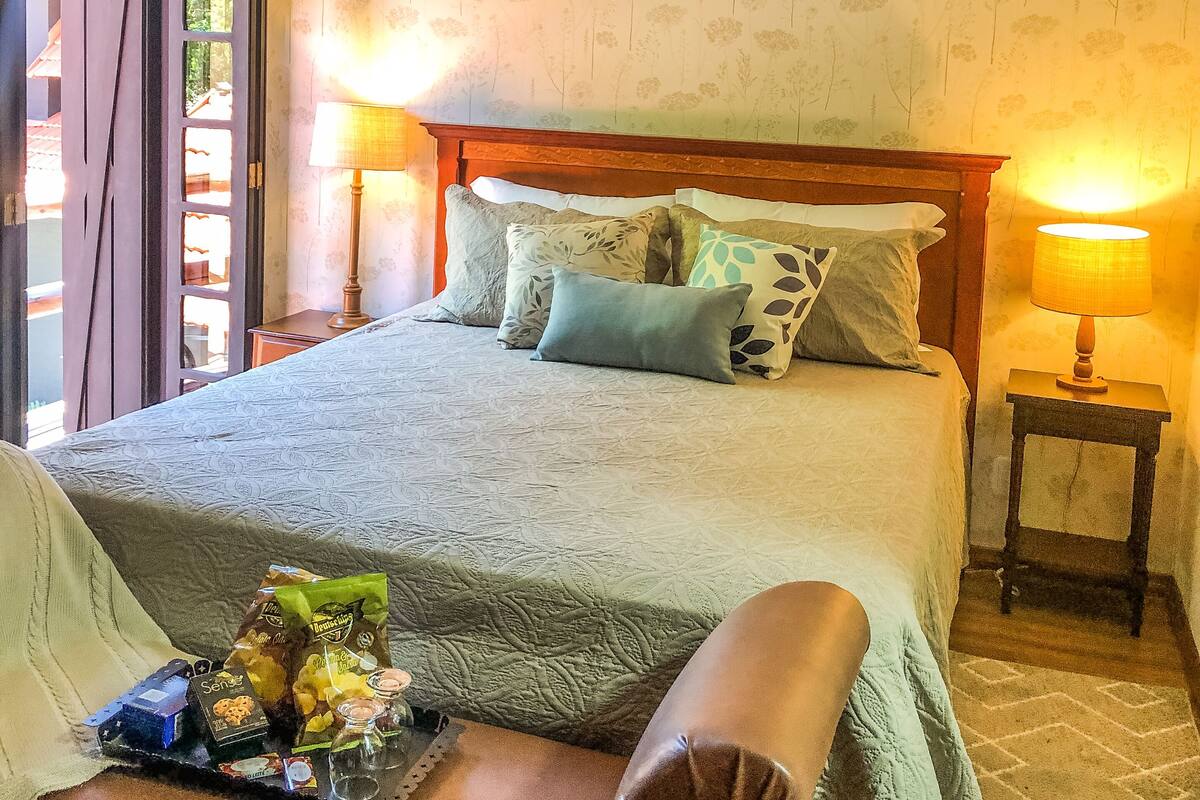 Une chambre à coucher avec un lit, des lampes de chevet, une fenêtre et un plafond en bois.