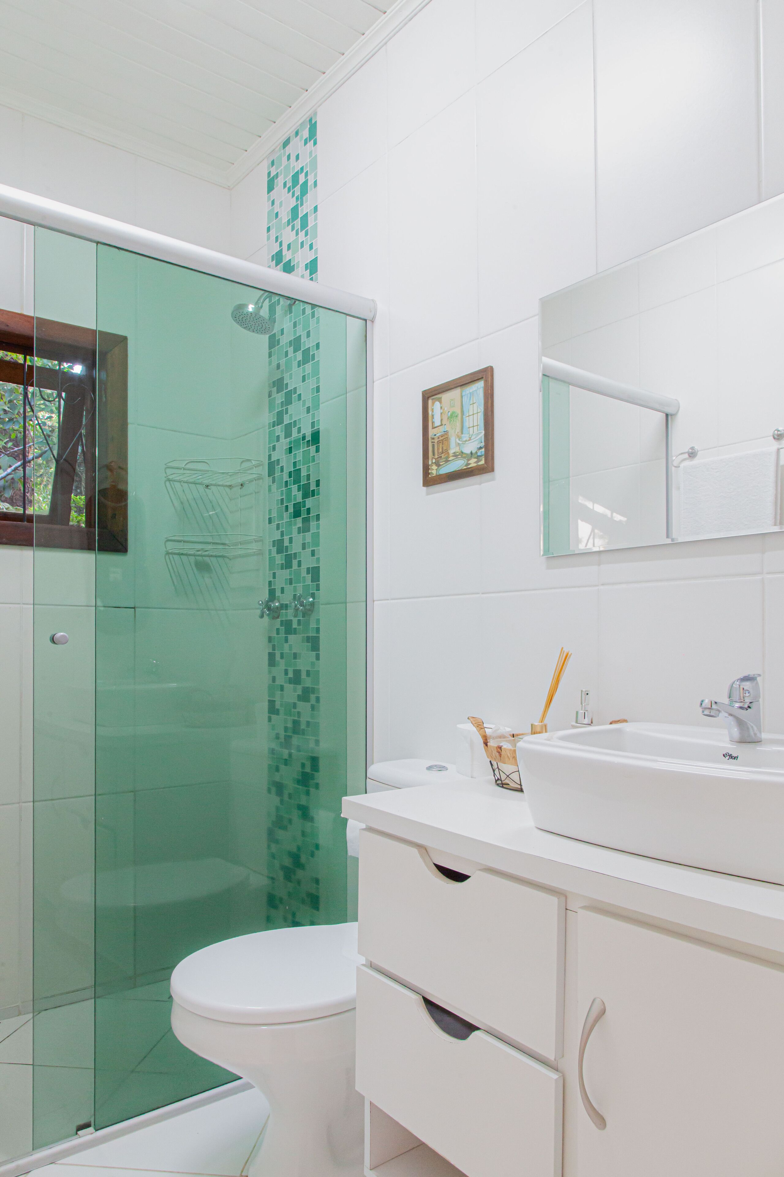 A modern bathroom with a glass shower enclosure, a white toilet, and a vanity with a mirror and sink.