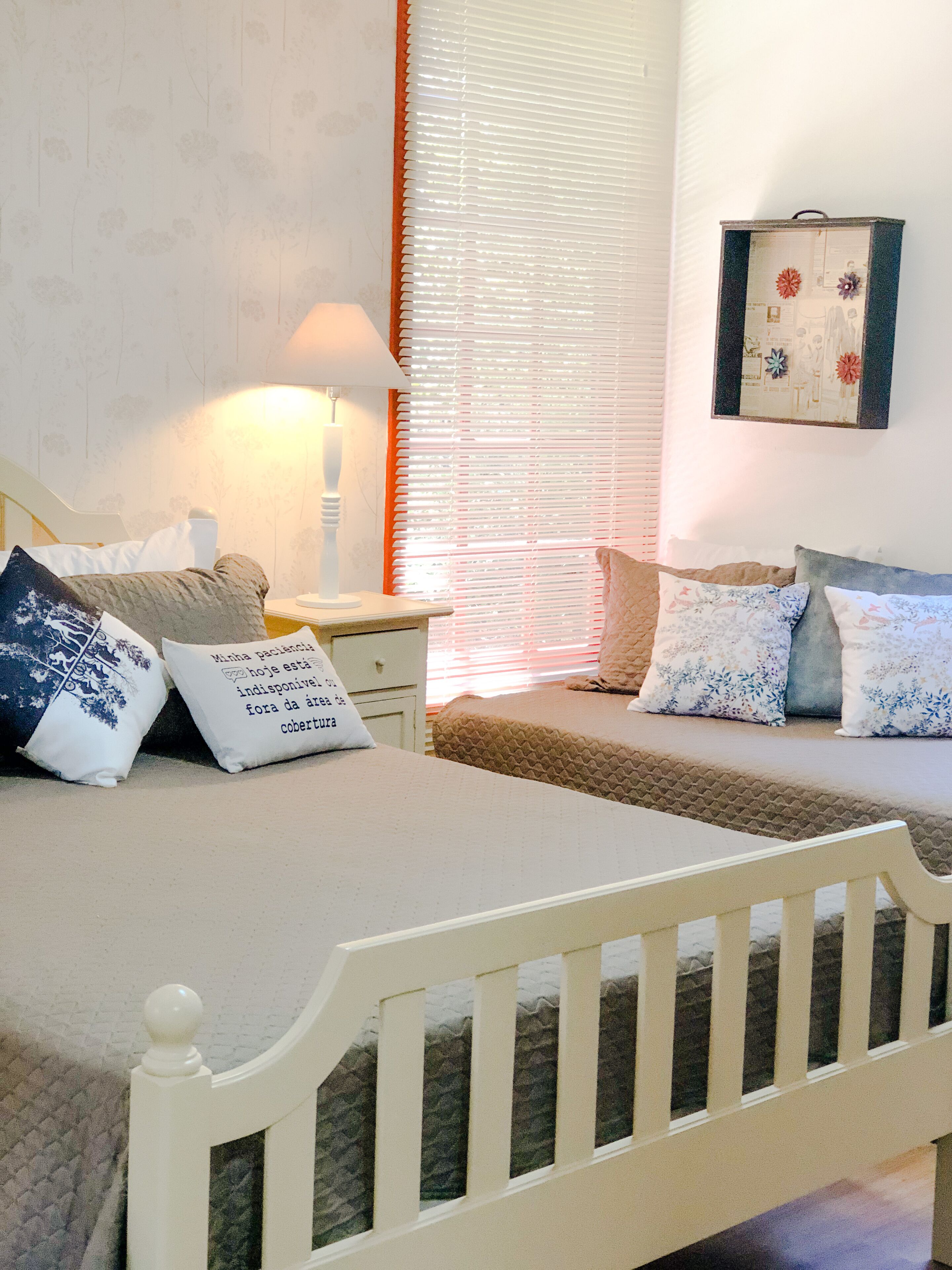 Une chambre à coucher avec un lit, une table de chevet, une lampe et une fenêtre avec des stores.