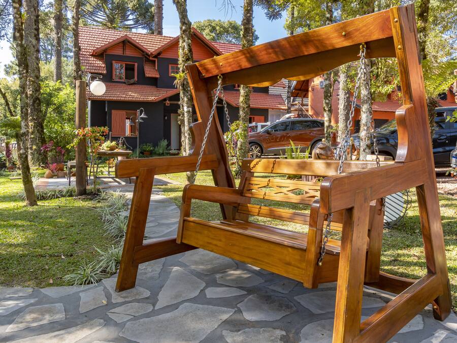 A wooden swing set in a garden with a house in the background.