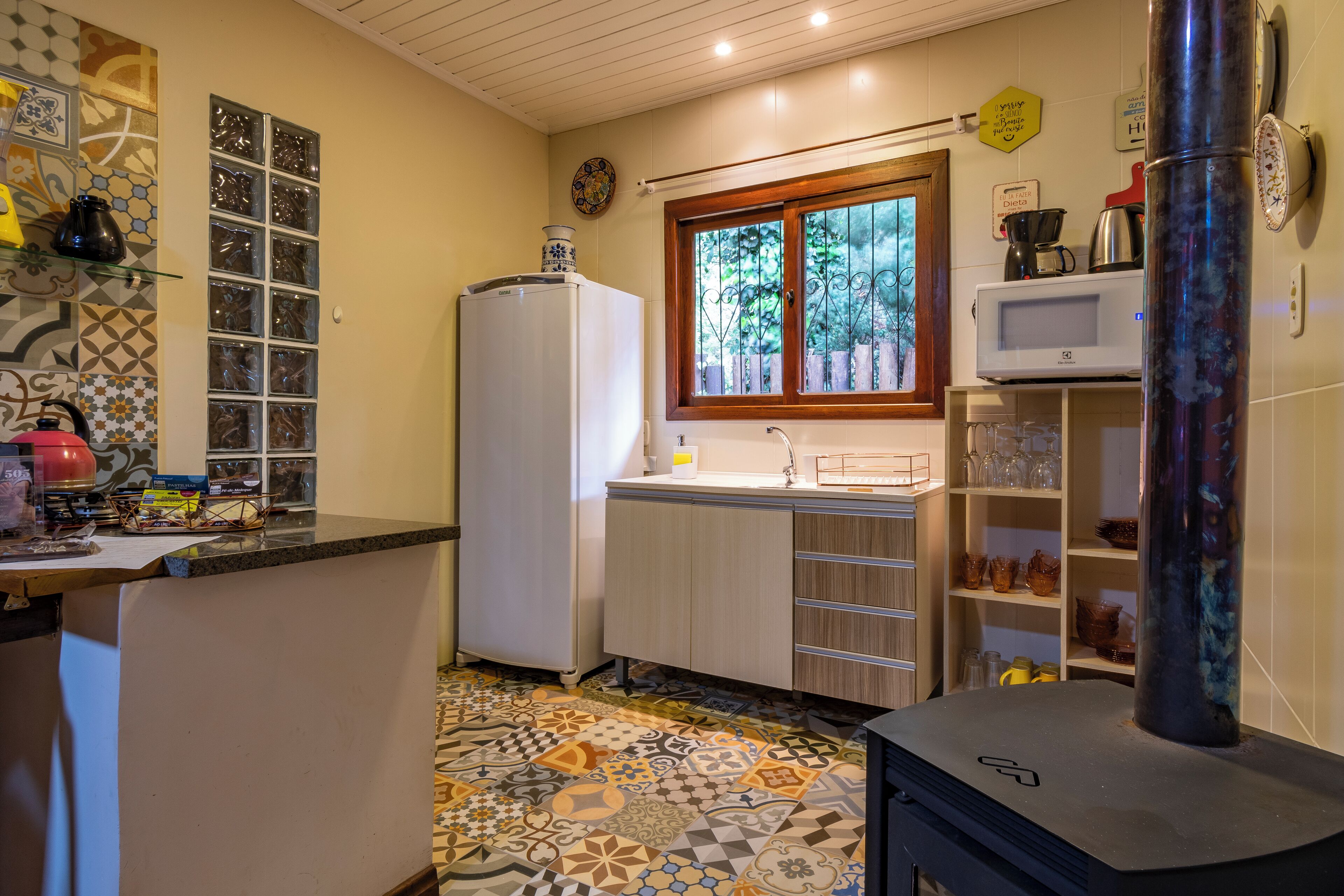 Una cocina compacta con piso estampado, un refrigerador, un microondas y una estufa.
