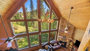 A cozy room with a large window, a fireplace, and a ceiling fan.