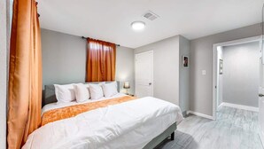 Un dormitorio con cama, cortinas, una puerta y una lámpara.