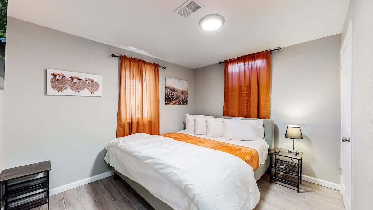 A neatly arranged bedroom with a bed, a bedside table with a lamp, and two wall-mounted paintings.