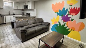 Una cocina moderna con armarios blancos, un sofá gris y una mesa de centro de madera.