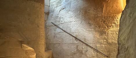 A stone staircase with a metal handrail, leading to an upper level.