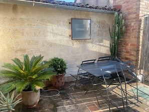 A patio with a metal table and chairs, potted plants, and a brick wall.