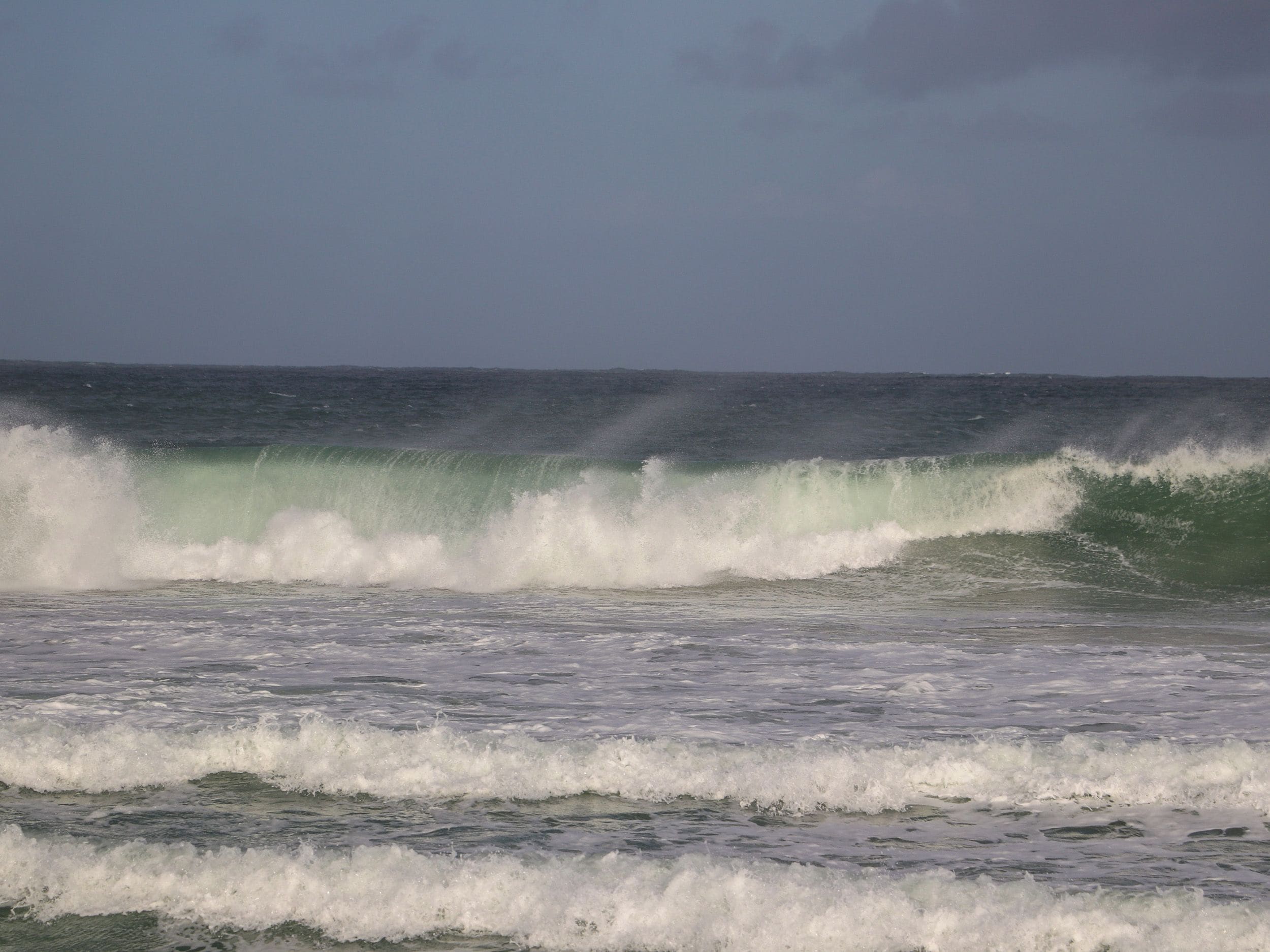 A view of the ocean with waves and a clear sky.