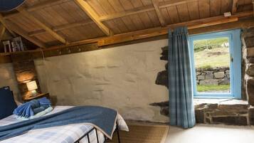 Un dormitorio acogedor con cama, mesita de noche, lámpara y vistas al exterior a través de una ventana.