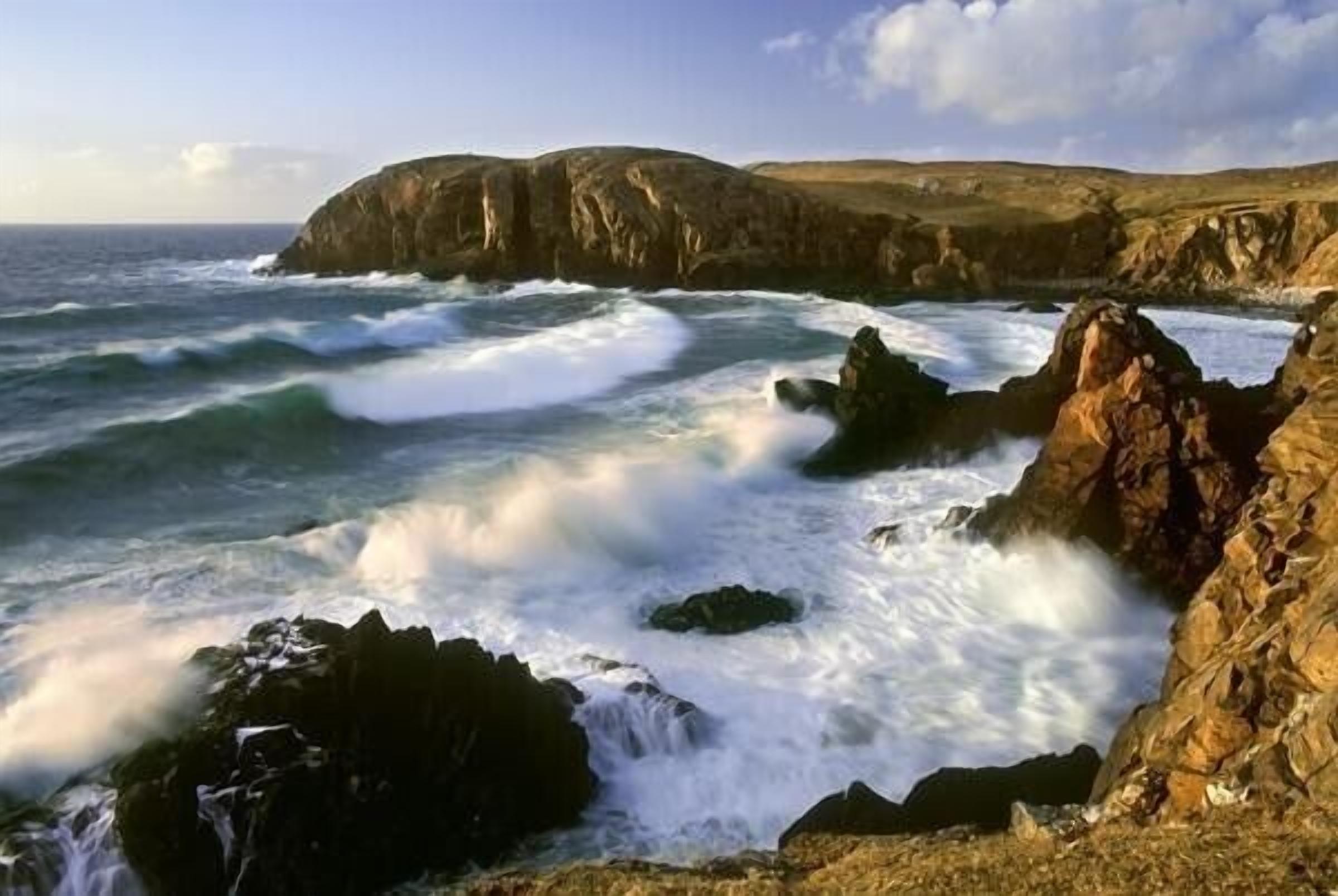 A coastal landscape with rocky cliffs and turbulent sea waves.