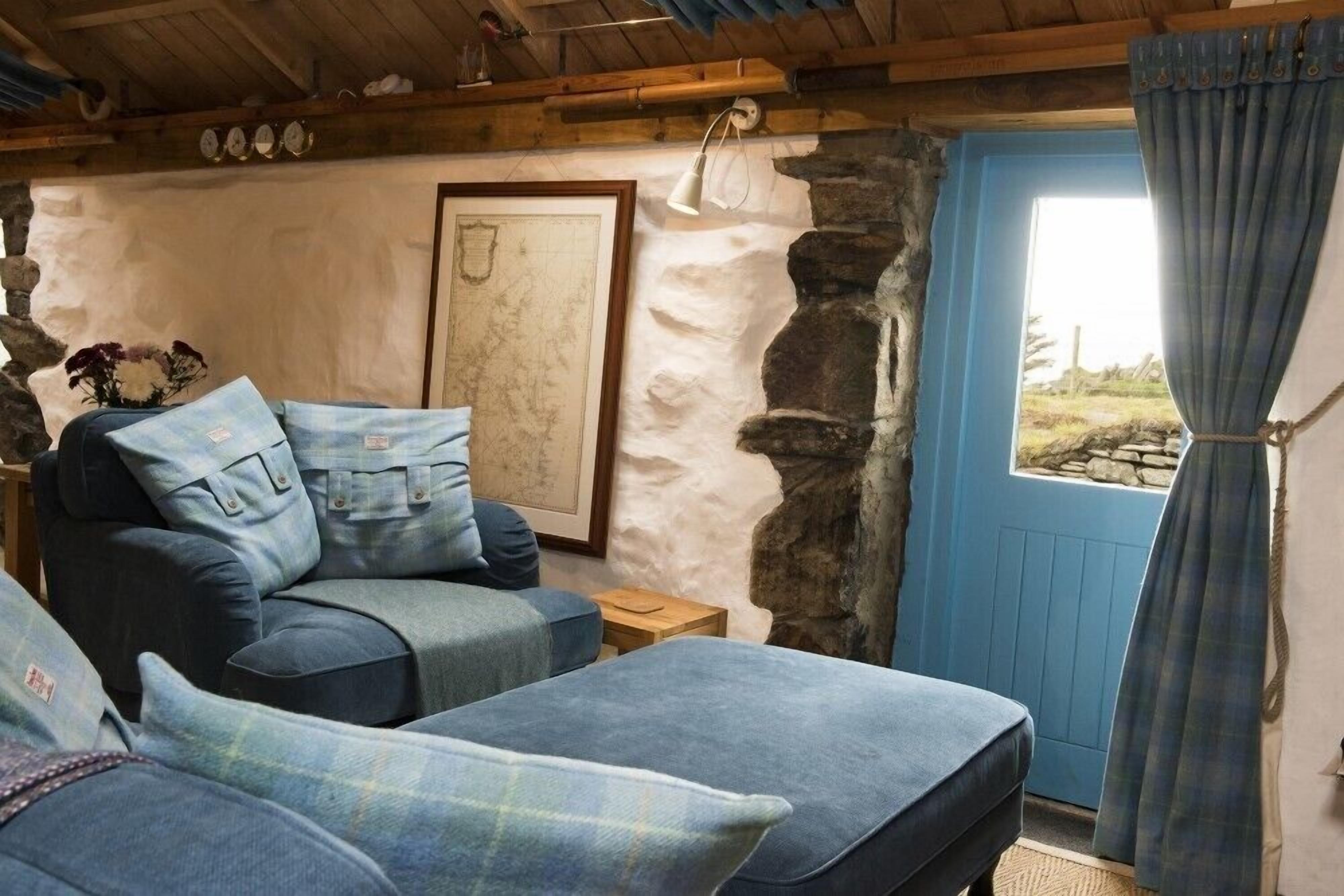A cozy room with a stone wall, a blue door, and a sofa with plaid cushions.