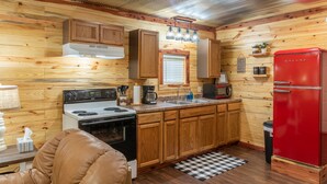 A kitchen with wooden cabinets, a stove, a sink, and a red refrigerator. - Escape to cozy 2-bedroom cabin near Ouachita Forest 4 min drive away (Mena)