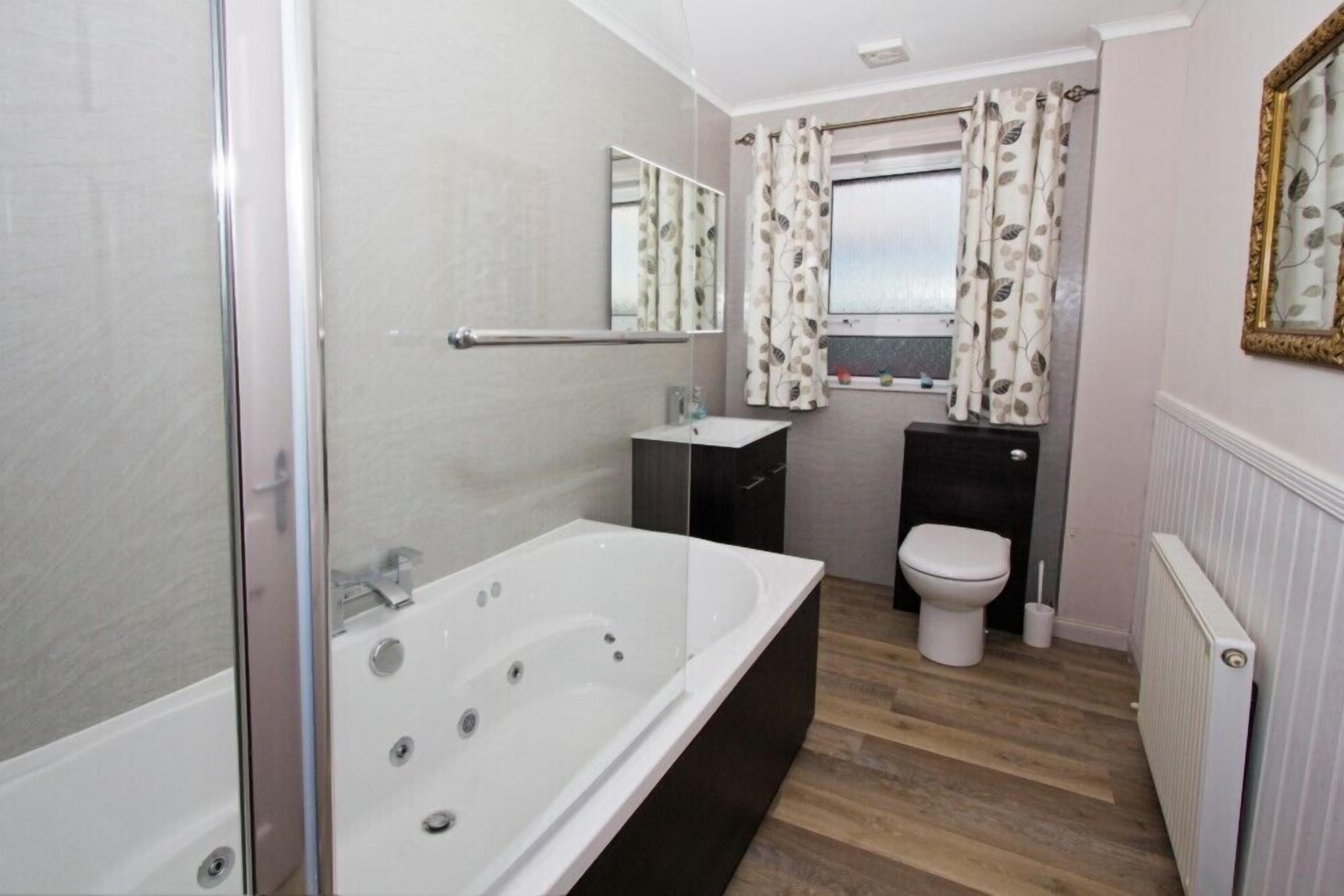 A modern bathroom with a large bathtub, a toilet, and a shower area.