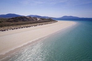 A wide, sandy beach with clear turquoise water and distant mountains. - Ceann an Loch Cottage (Isle of Lewis)