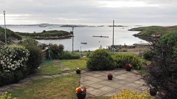 A garden with a view of a body of water, a paved area, and some potted plants.