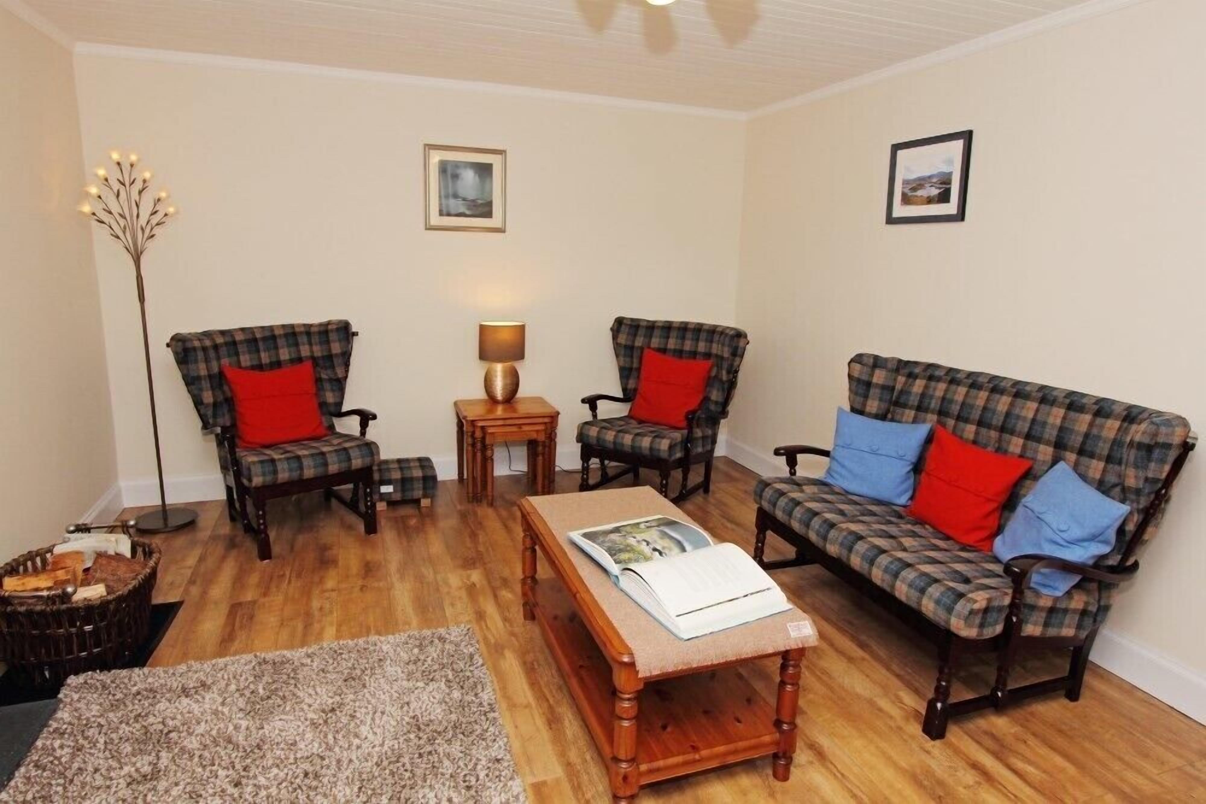A cozy living room with two plaid sofas, a wooden coffee table, and a floor lamp.