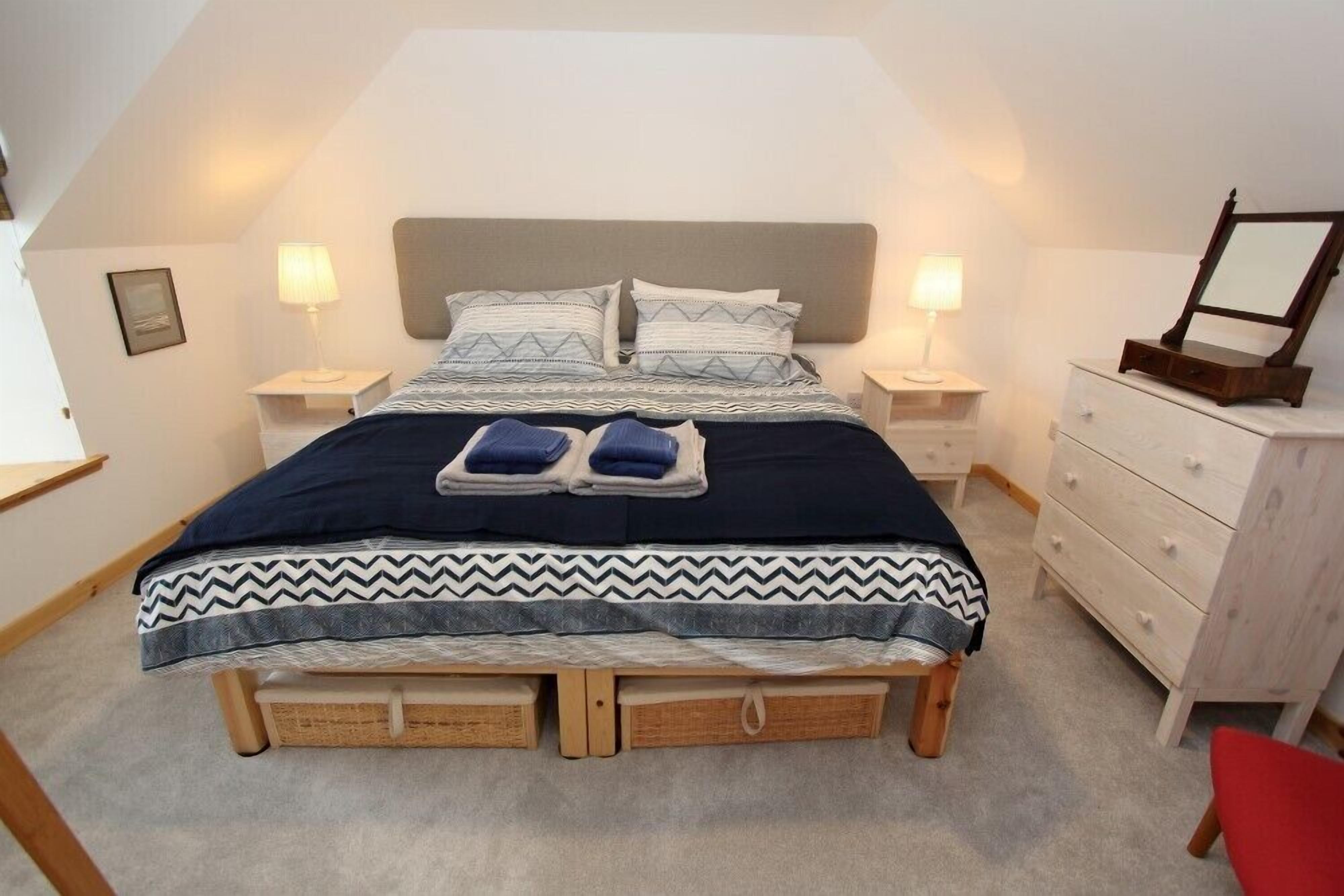 Een slaapkamer met een bed, twee nachtkastjes, een kaptafel en een spiegel.