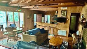 Ein gemütliches Blockhausschlafzimmer mit Holzbalkendecke, einer Couch, einem Couchtisch, einem Fernseher und einer Bar.