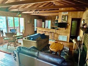 Ein gemütliches Blockhausschlafzimmer mit Holzbalkendecke, einer Couch, einem Couchtisch, einem Fernseher und einer Bar.