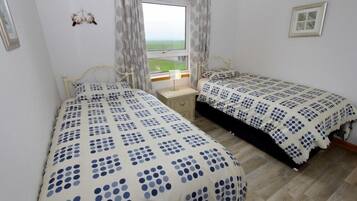Een slaapkamer met twee bedden, een raam met uitzicht en een klein nachtkastje.