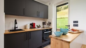Una cocina moderna con armarios oscuros, encimera de madera y vistas al exterior.