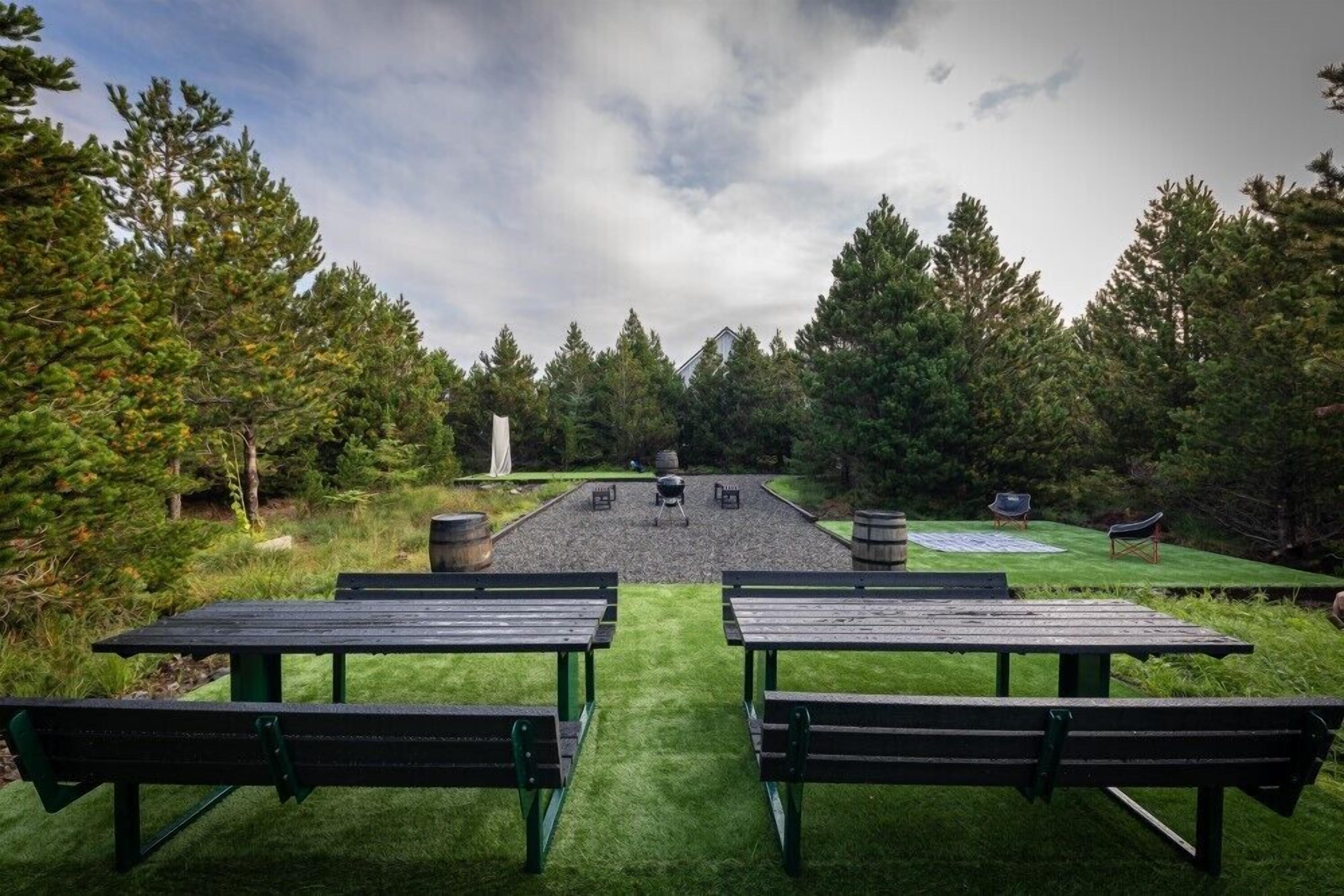 An outdoor seating area with picnic tables and a central fire pit.